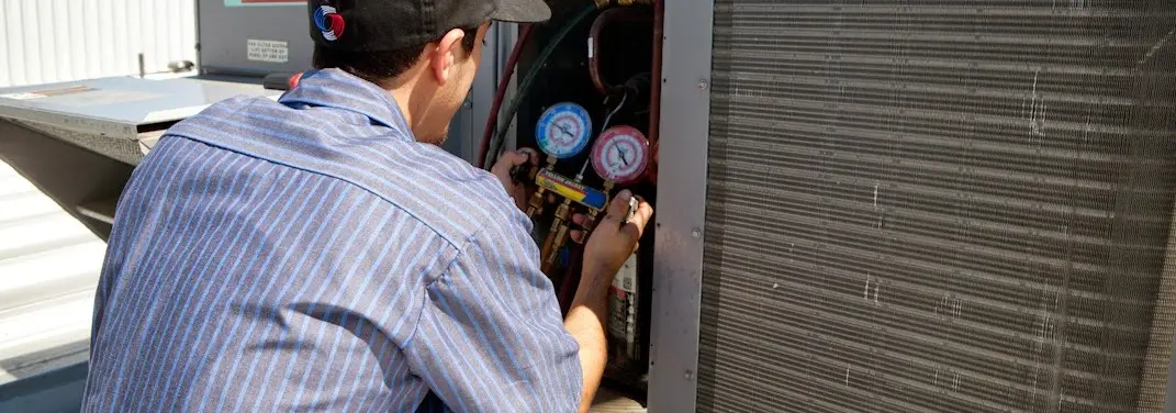 HVAC technician servicing a condenser unit in Smiths Station
